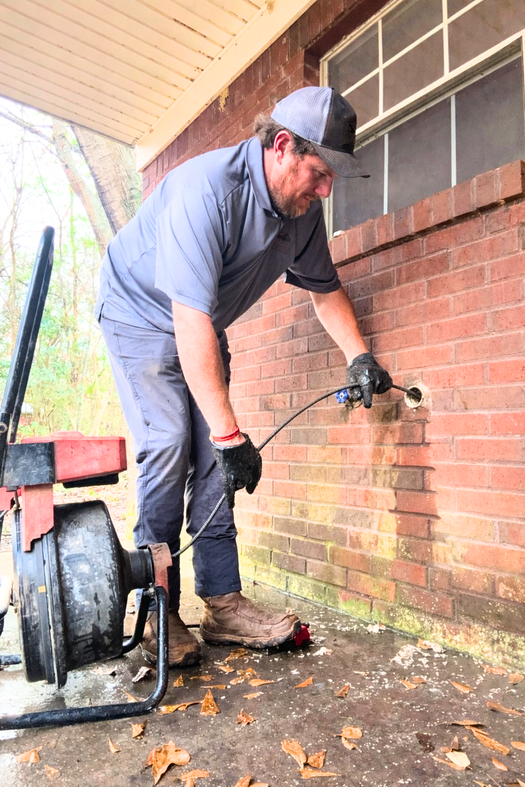Technician performing professional drain cleaning service on a residential sewer line cleanout.